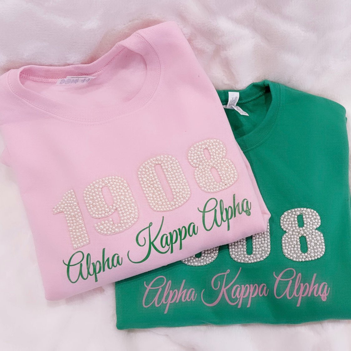 1908 pearl-embellished sweatshirt available in pink or green, designed for the women of Alpha Kappa Alpha Sorority, Inc., to showcase their elegance and sisterhood.