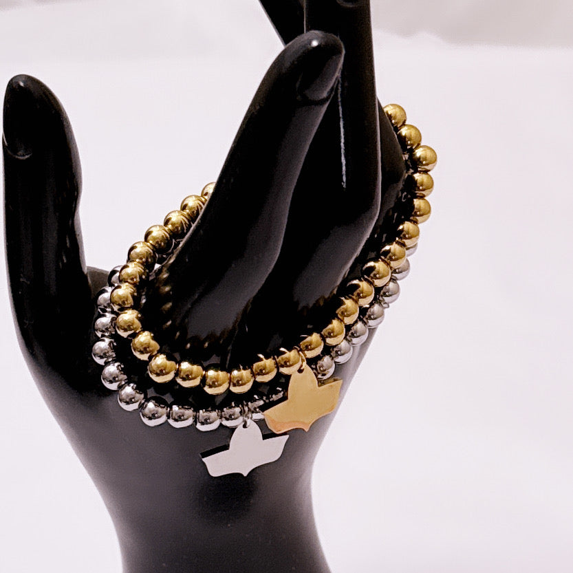 Gold and silver beaded stretch bracelets with official Alpha Kappa Alpha Ivy charms displayed on a black mannequin hand, highlighting the dual metal finishes.
