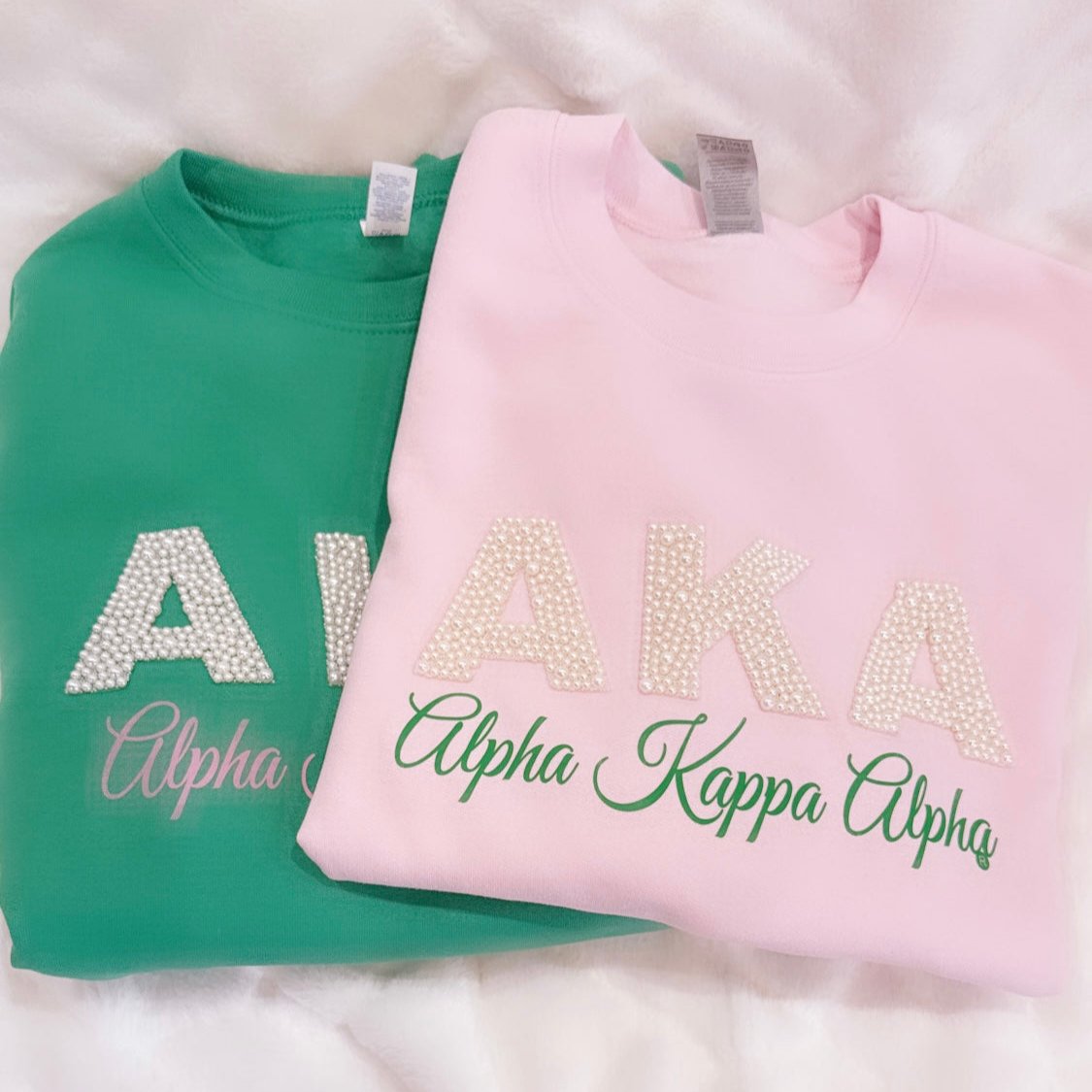 "Unisex AKA Pearl Embellished Sweatshirt in pink or green, featuring the iconic 'AKA' in pearls, representing the legacy of Alpha Kappa Alpha Sorority, Inc. A stylish and elegant way to show sorority pride."