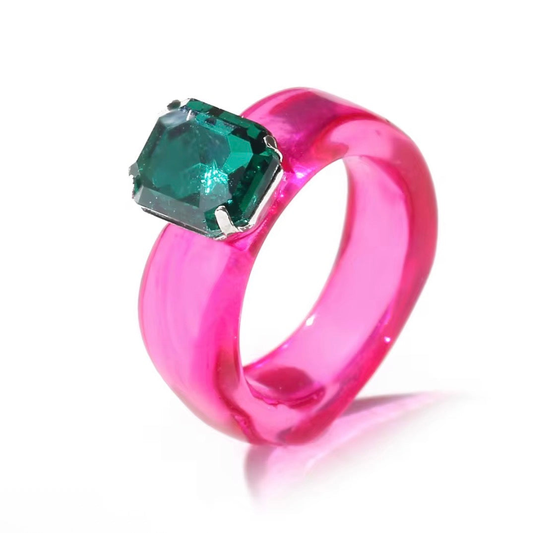 Pink ring with a green gemstone on a white background