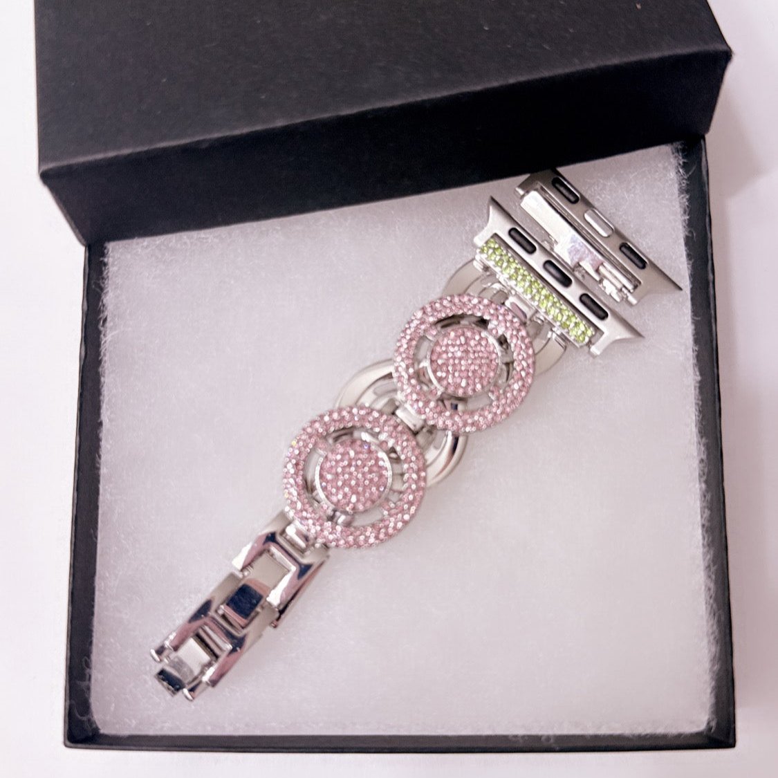 A high-quality stainless steel adjustable Apple Watch band with pink and green stones, designed for both elegance and individuality. The band is shown complementing an Apple Watch, highlighting its sophisticated style. Available in two size ranges (38/40/41mm and 42/44/45mm), it features an adjustable design for a comfortable fit and is compatible with Apple Watch Series 1-9 and Ultra. Perfect for formal events or casual wear.