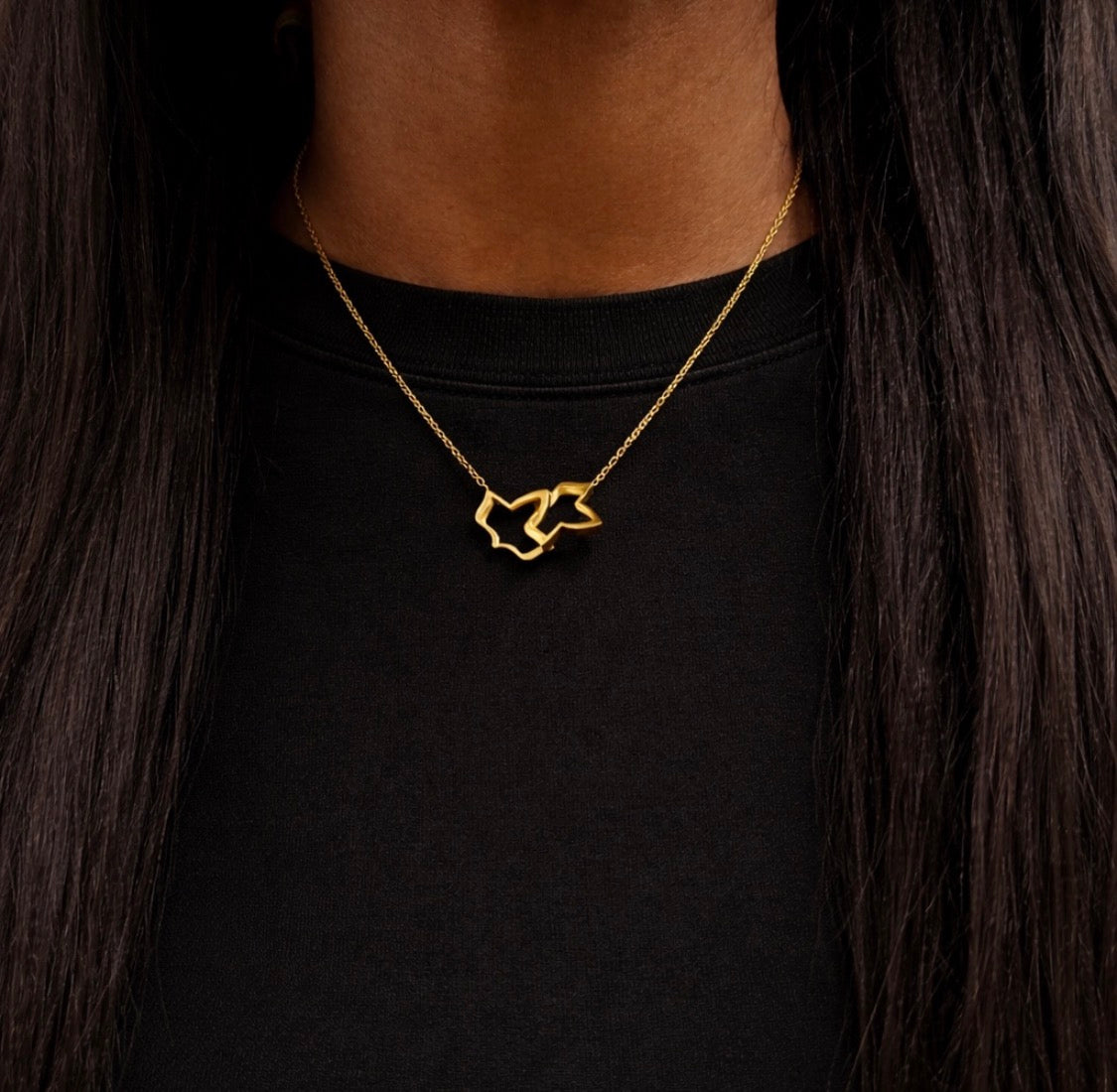 Gold necklace with a star pendant worn by a person against a black background