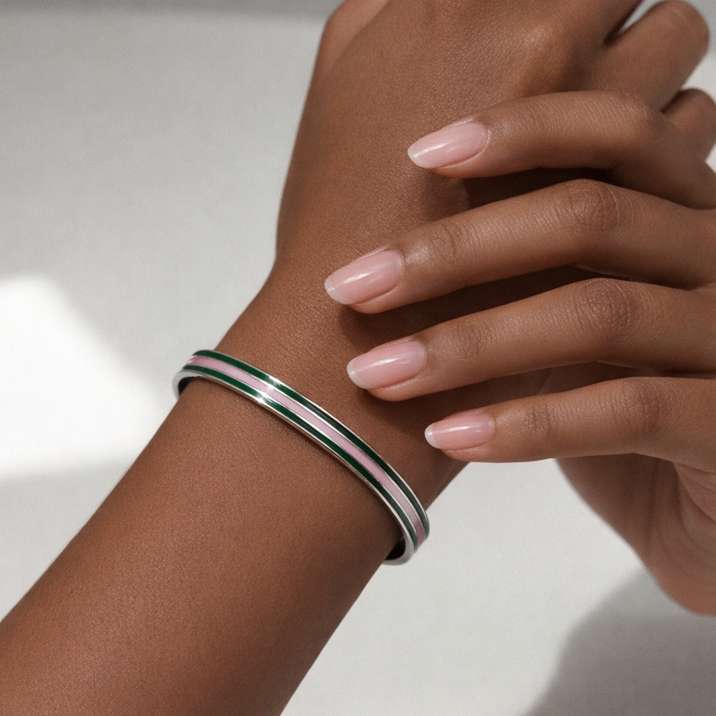 Close-up of a hand wearing a silver bracelet on a light background