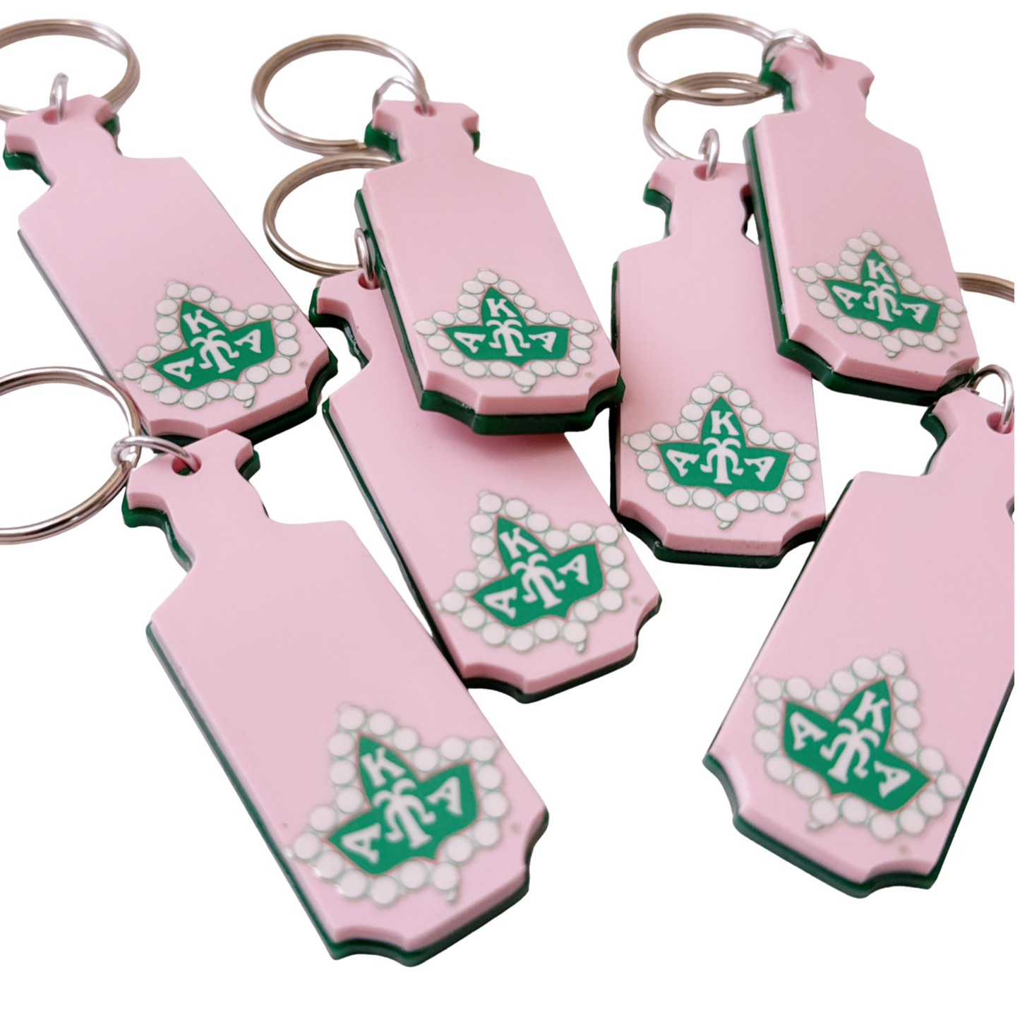 Set of pink keychains with green designs on a white background for AKA members.