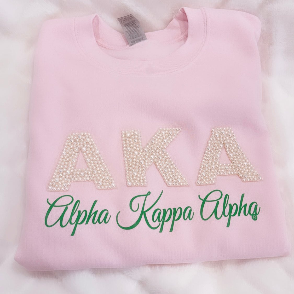 "Pink AKA Pearl Embellished Sweatshirt featuring 'AKA' in pearl accents, representing the legacy of Alpha Kappa Alpha Sorority, Inc., designed for elegance and sorority pride."