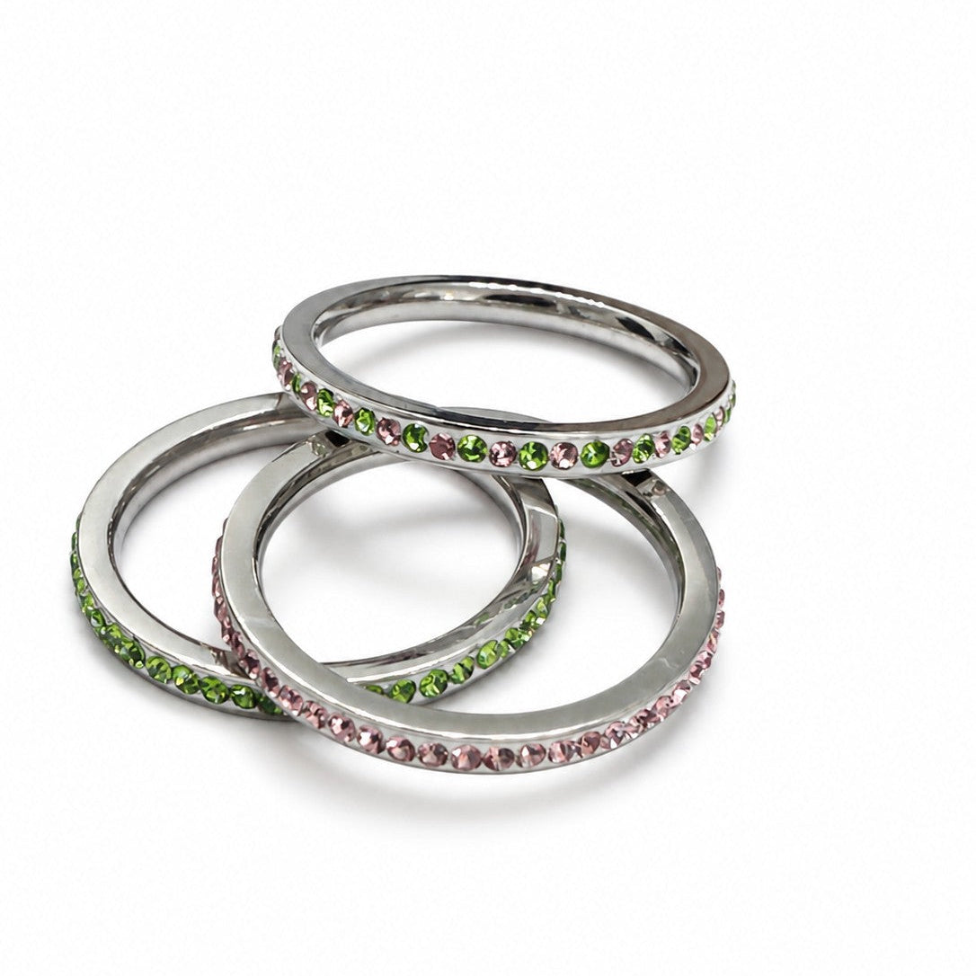 Three stainless steel stacking rings featuring pink, green, and alternating pink and green cubic zirconia stones displayed on a white background.