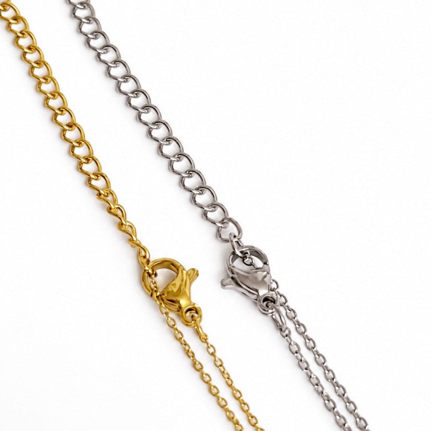 Closeup of gold and silver necklace extender chains with lobster clasps and adjustable links on a white background.