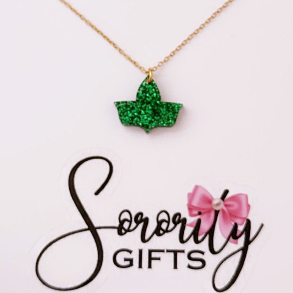 Green glitter ivy leaf pendant necklace with a gold chain, displayed on a white backing card with the "Sorority Gifts" logo featuring a pink bow.