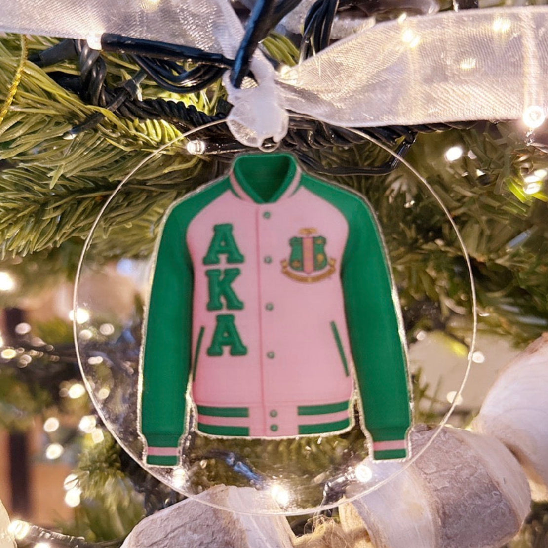 Decorative ornament of a pink and green varsity jacket with 'AKA' letters on a Christmas tree.
