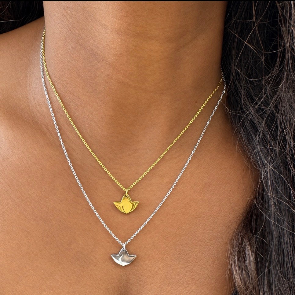 Model wearing layered gold and silver ivy leaf pendant necklaces, with the gold necklace resting above the silver.
