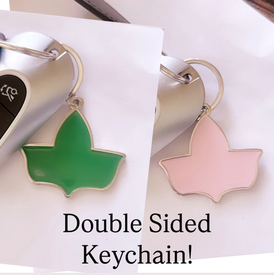 Double-sided enamel keychain featuring the official Ivy Leaf logo of Alpha Kappa Alpha Sorority, Inc., with one side in pink and the other in green, attached to a silver keyring.