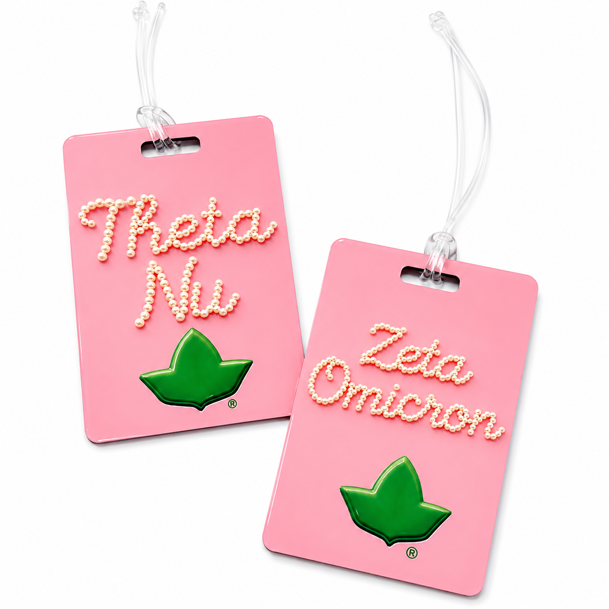 Two pink luggage tags with clear hanging strings, featuring white pearl-style lettering that reads 'Theta Nu' and 'Zeta Omicron' above a green leaf emblem, on a white background.