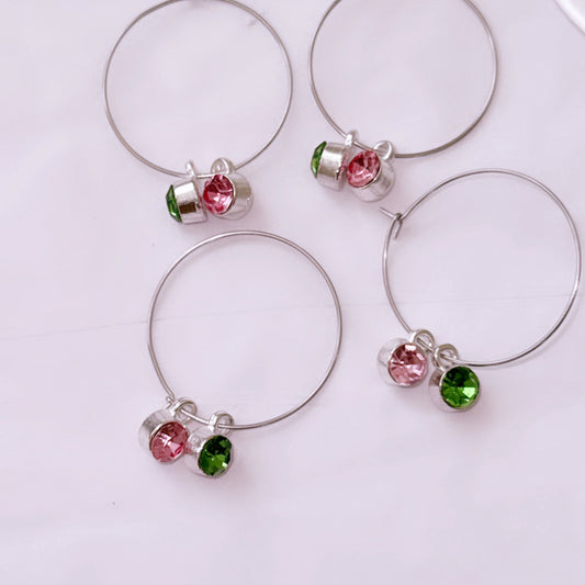 Set of four silver-tone wine glass charms with sparkling pink and green crystals, perfect for sorority celebrations and gifts.