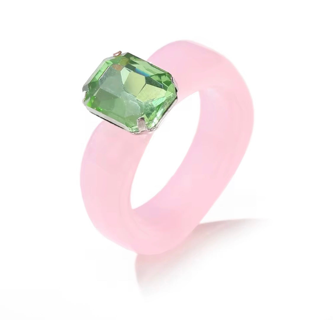 Pink ring with a green gemstone on a white background