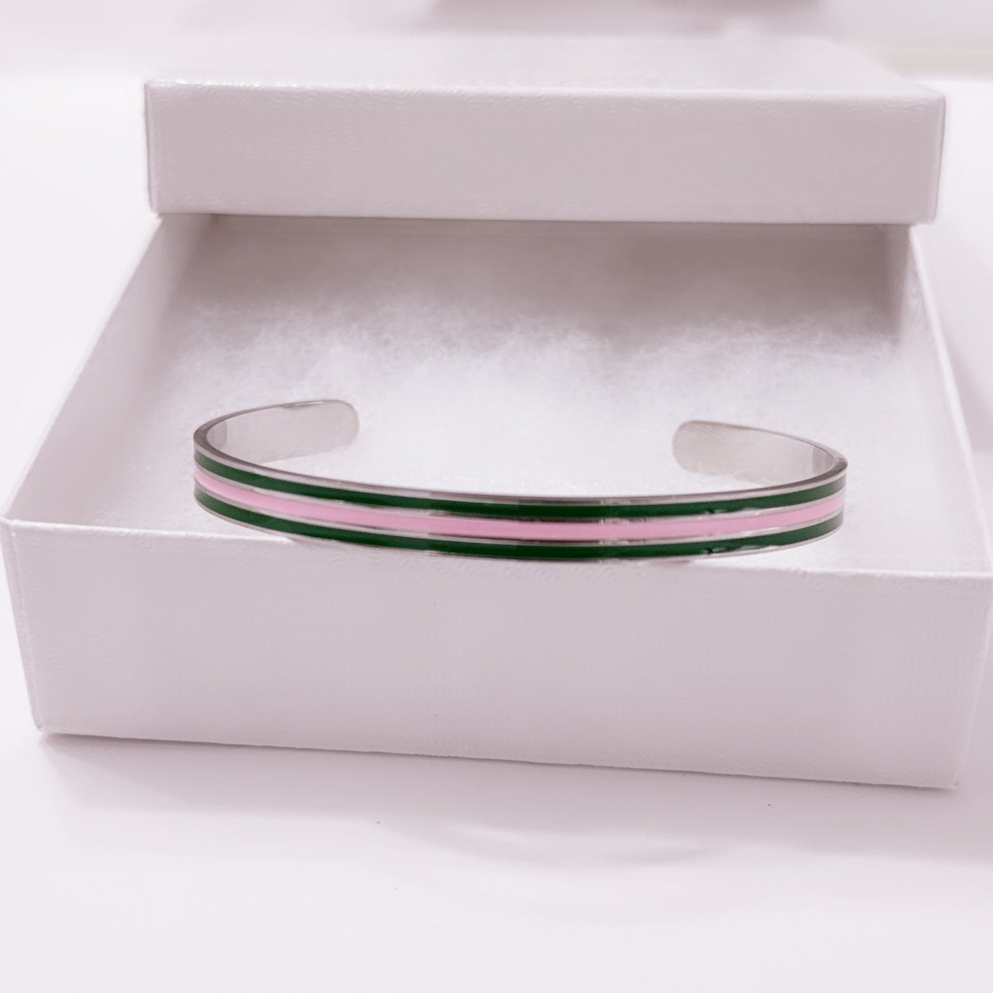 Pink and green striped enamel cuff bracelet on white background