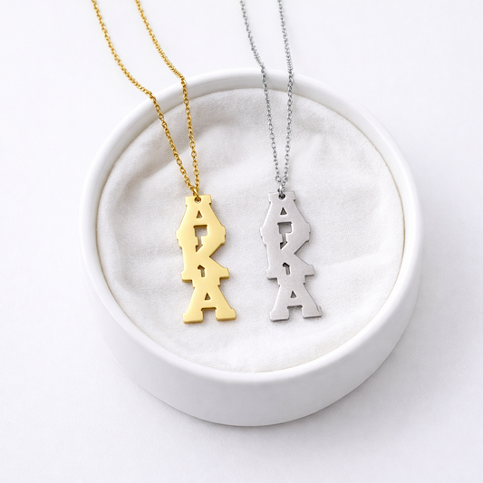 Stainless steel AKA charm necklace in gold and silver plated finish on white background