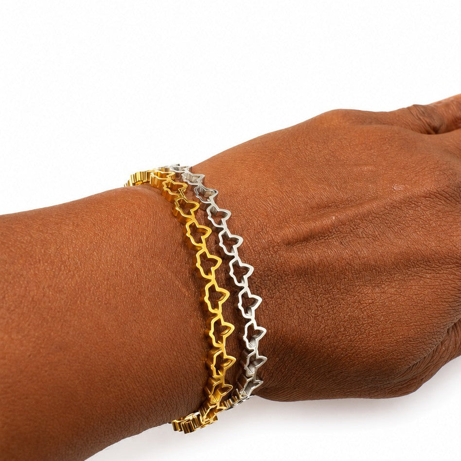 Model wearing adjustable gold and silver stainless steel ivy cuff bracelets with elegant ivy cutout design on wrist against a white background.