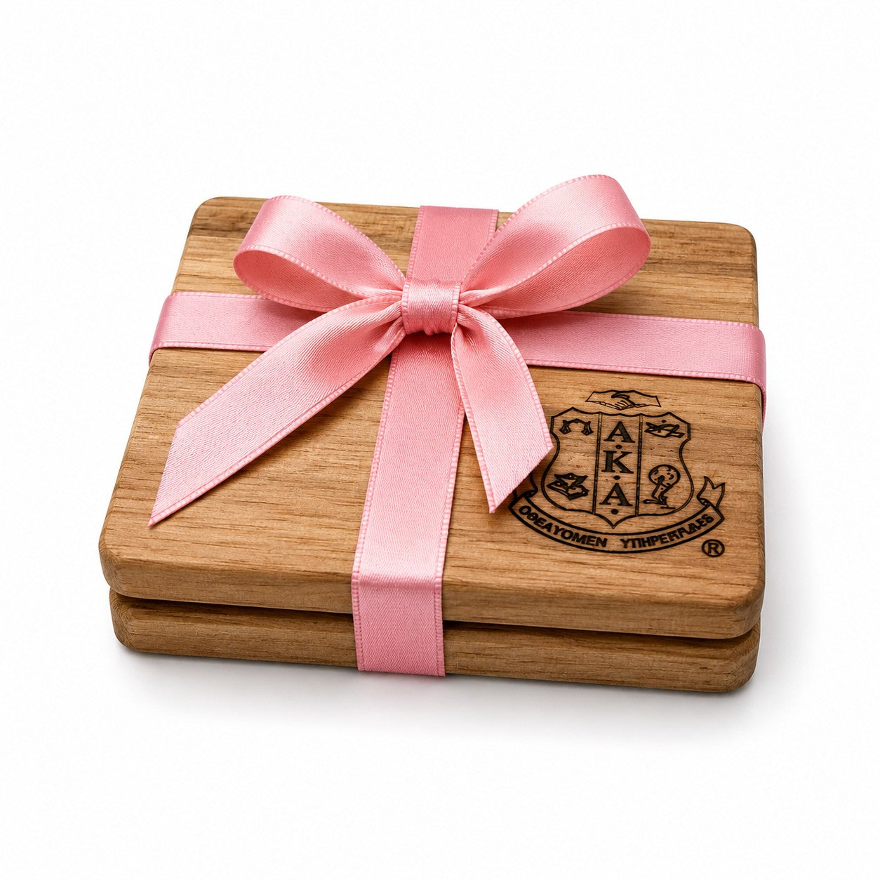 Gift set of two 4 x 4 inch Alpha Kappa Alpha Sorority, Inc.® engraved acacia wood coasters wrapped with a pink satin ribbon and bow. Each coaster features a unique natural wood grain and includes non-slip silicone dots to help protect surfaces.