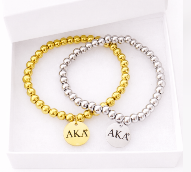 Alpha Kappa Alpha licensed gold and silver beaded stretch bracelets with engraved AKA charms photographed on a pure white background