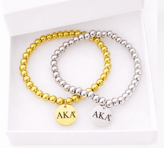 Alpha Kappa Alpha licensed gold and silver beaded stretch bracelets with engraved AKA charms photographed on a pure white background