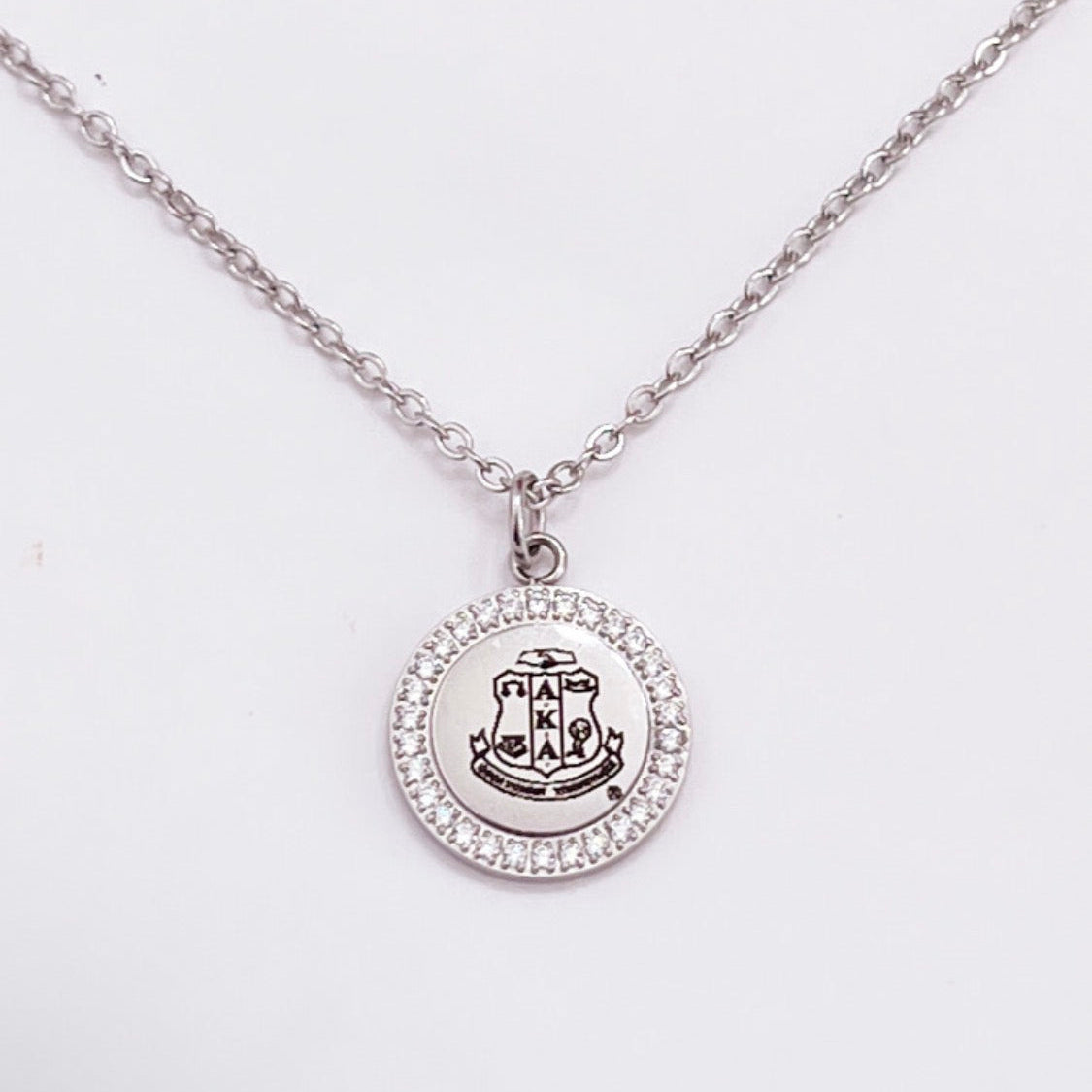 Alpha Kappa Alpha stainless steel shield charm necklace featuring a crystal halo pendant on an adjustable 16 to 18 inch silver chain