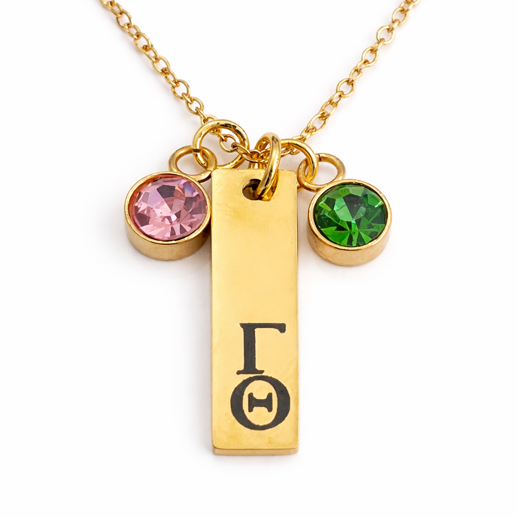 Gold personalized stainless steel charm necklace engraved with Greek letters and accented with pink and green charms close up detail