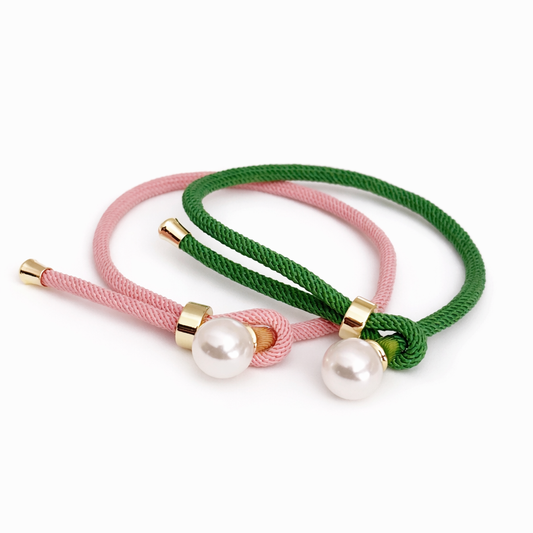 Pink and green adjustable rope bracelets with pearl charms displayed together