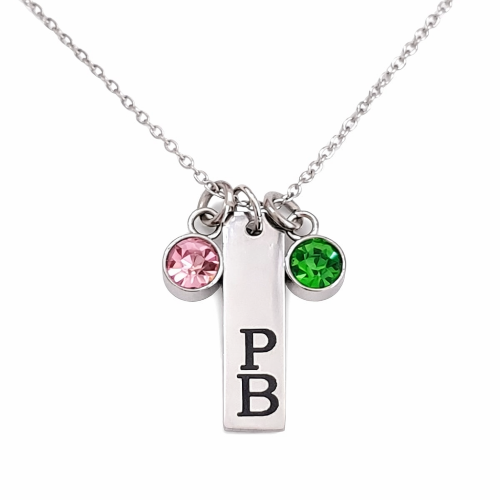 Silver personalized stainless steel charm necklace engraved with Greek letters and accented with pink and green charms close up detail