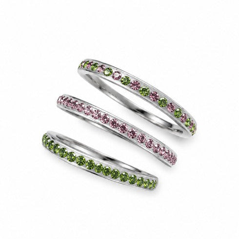 Three stainless steel stacking rings with pink, green, and alternating pink and green cubic zirconia stones arranged on a white background.