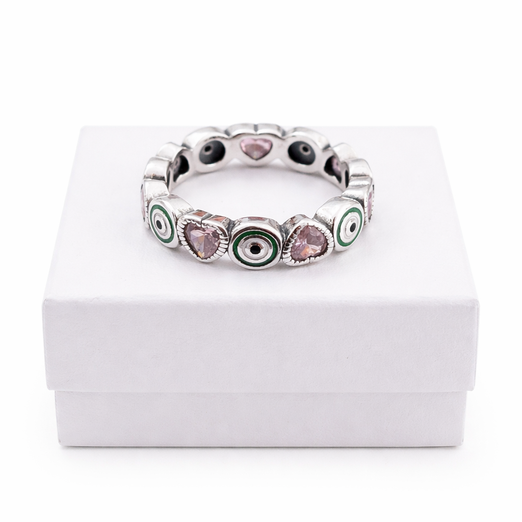 Sterling silver eternity ring with pink heart stones and green enamel accents displayed on a pure white gift box