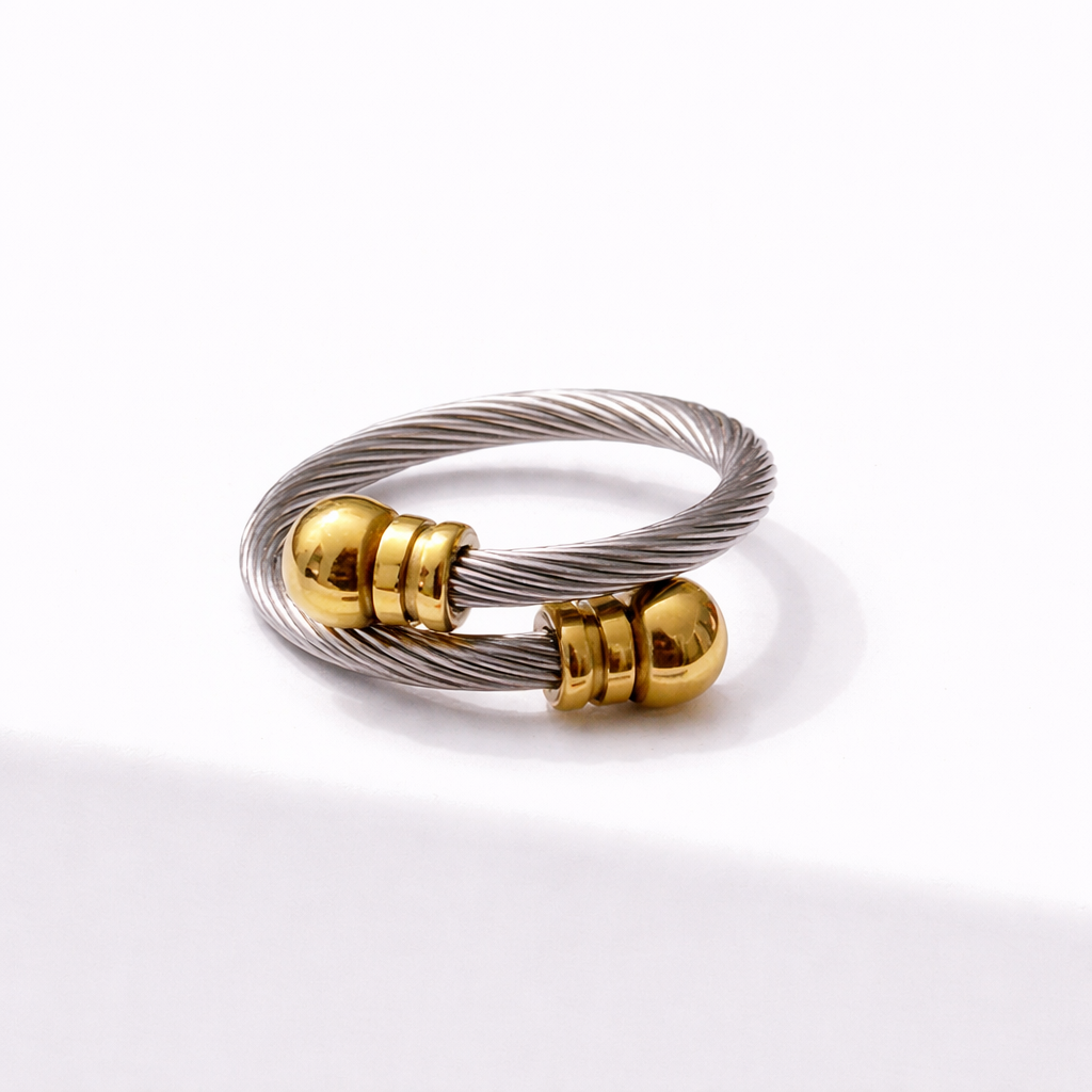 Two-tone stainless steel adjustable cable ring with silver and gold finish on white background